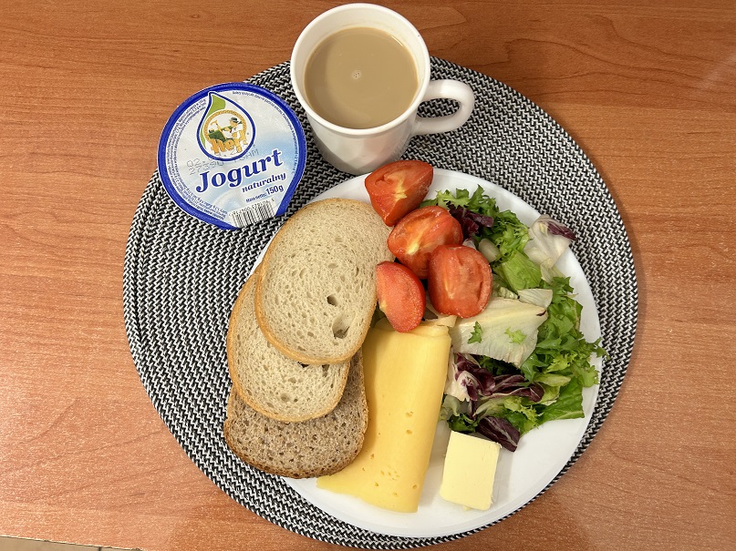 Na zdjęciu: Jogurt naturalny, Kawa zbożowa z mlekiem, Chleb mieszany pszenno-żytni, Chleb Graham, Masło extra 82%, Ser żółty, Pomidor, Mix sałat